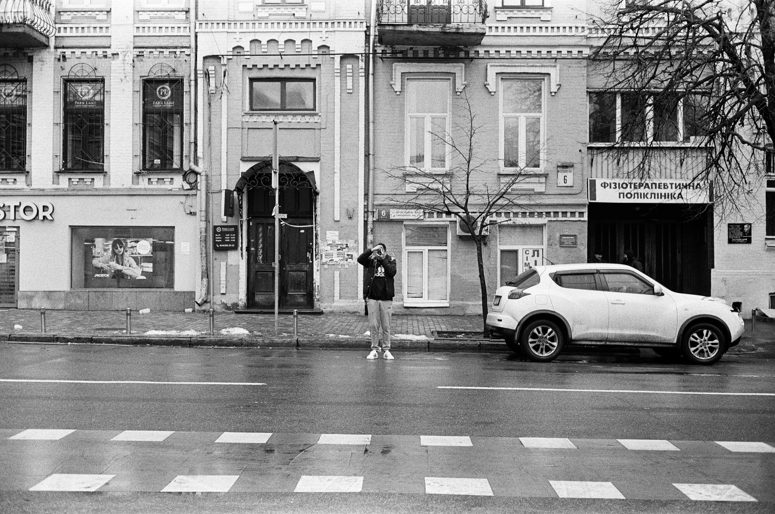 grayscale photo of woman walking on pedestrian lane